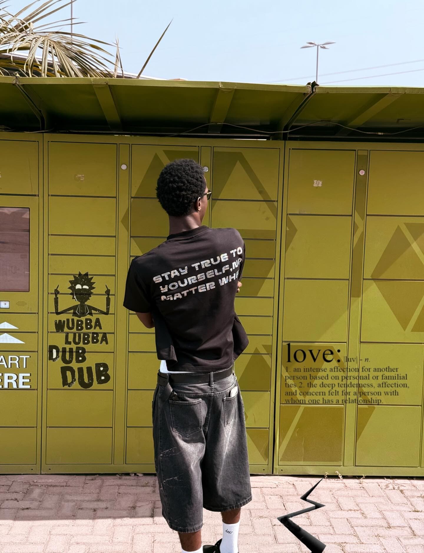 Black back-text tee by yellow wall